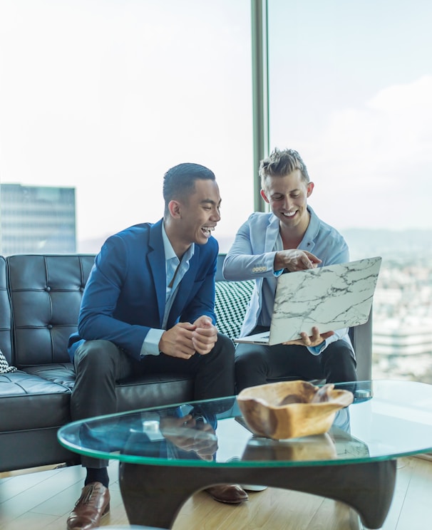 two men in suit sitting on sofa